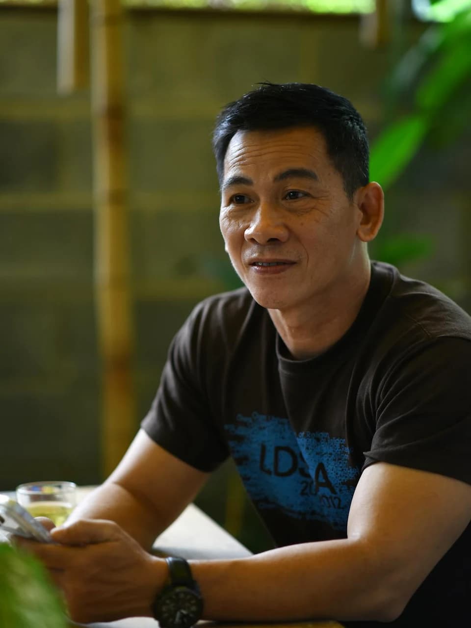 カフェのような落ち着いた空間で自然に微笑む男性のポートレート